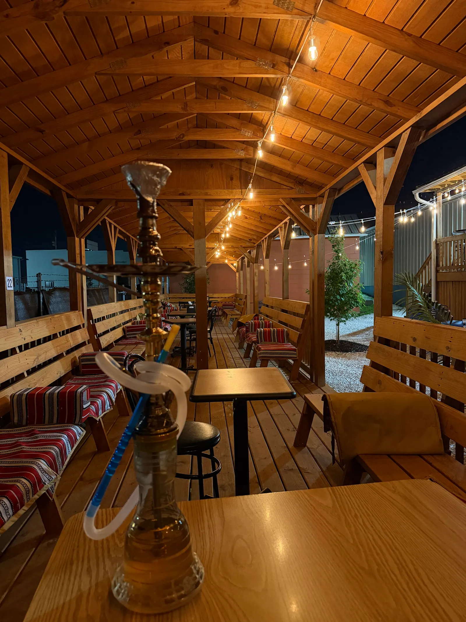 A hookah on a cabana table in the Middle Beast backyard, string lights overhead