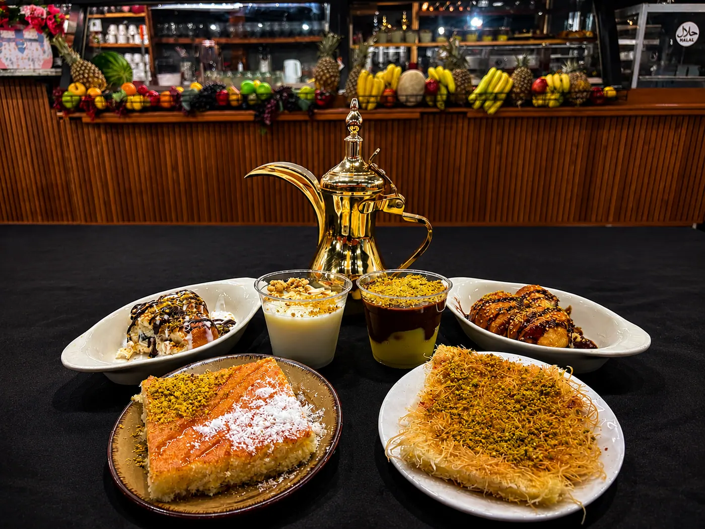 Kunafa, basbousa, and custard desserts around a gold dallah coffee pot