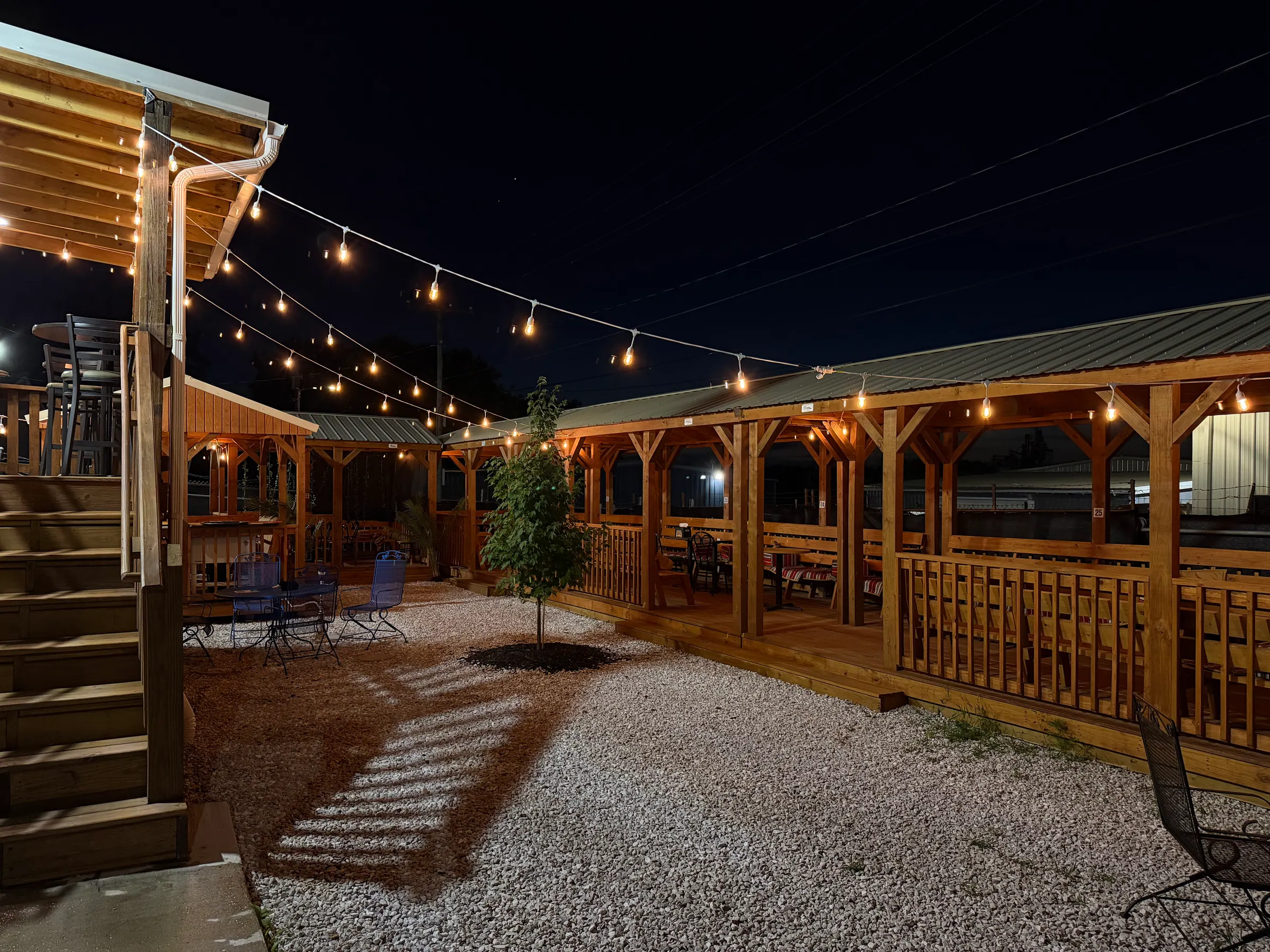 Middle Beast backyard at night: wooden cabanas under warm string lights